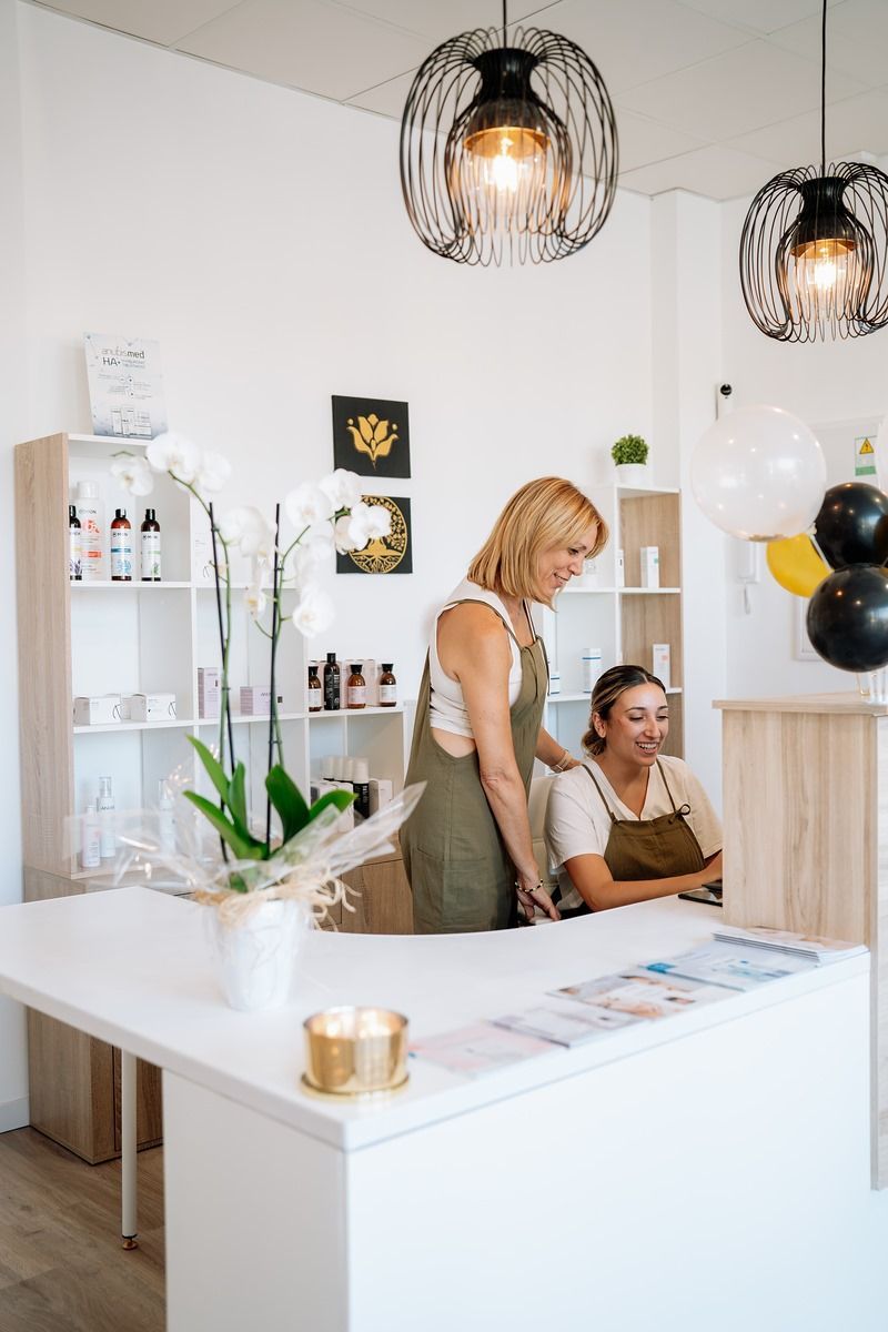 Dos mujeres están de pie frente a un mostrador en un salón.