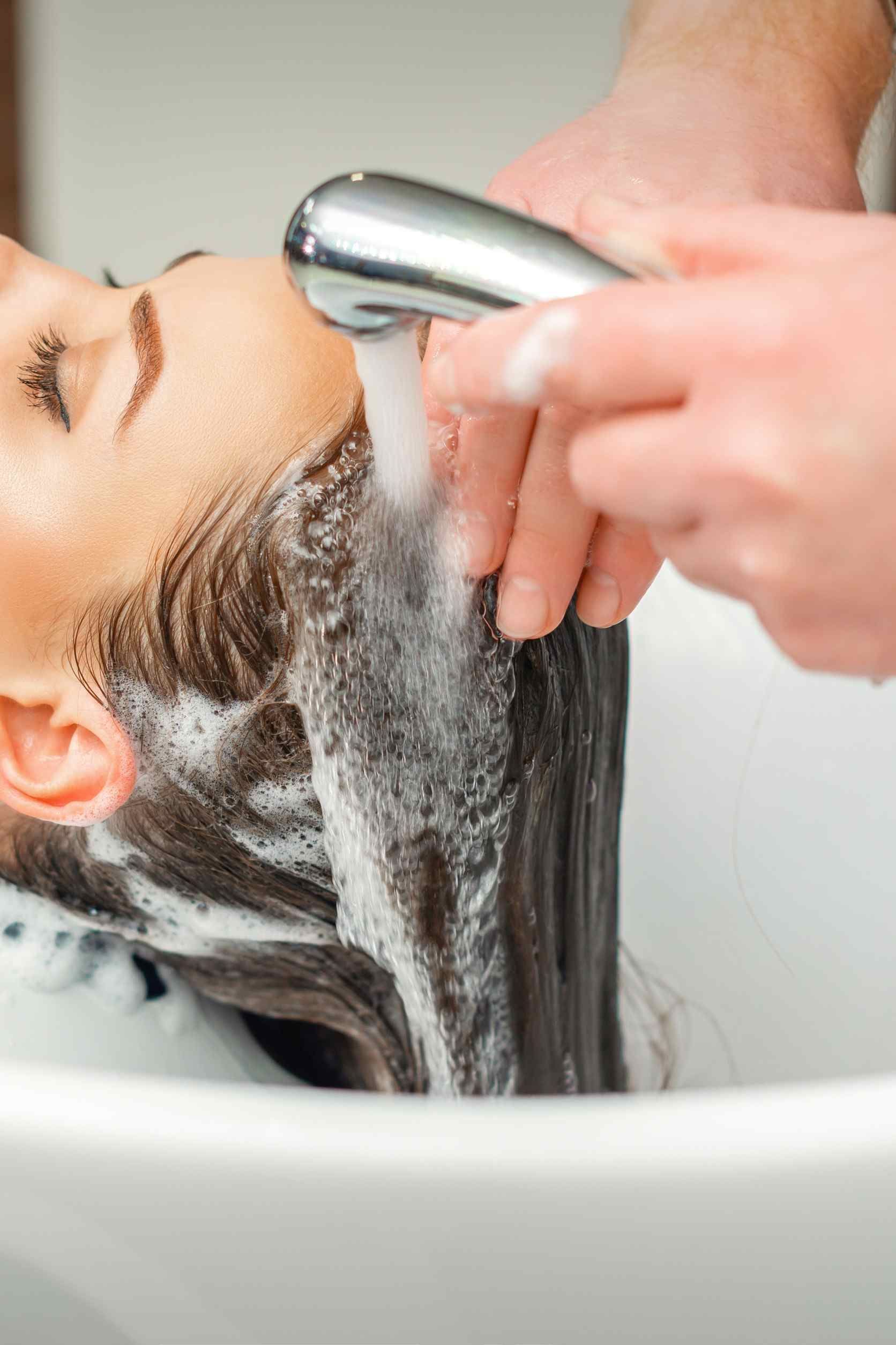 Una mujer se lava el cabello en el lavabo de una peluquería.