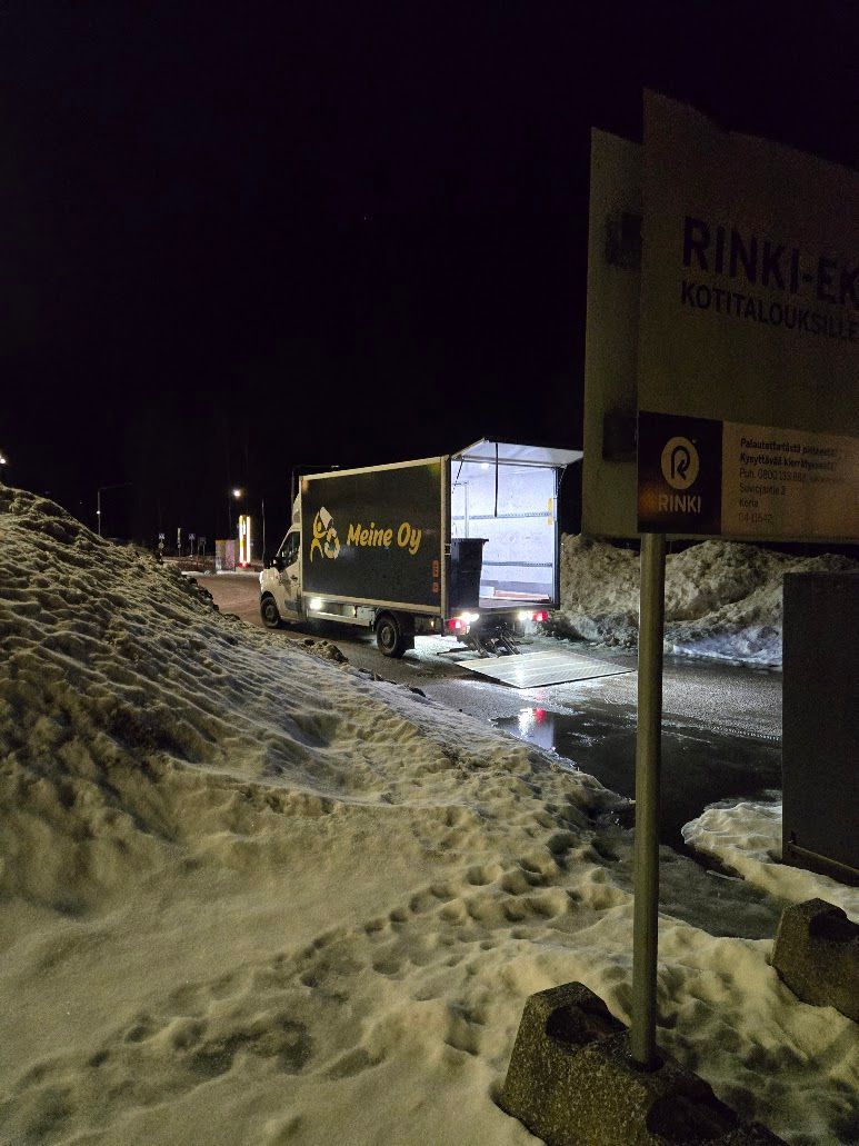 Kuorma-auto pysäköitynä kierrätyskeskuksen sisäänkäynnille yöllä, lastausalue avoinna, lunta ympärillä.