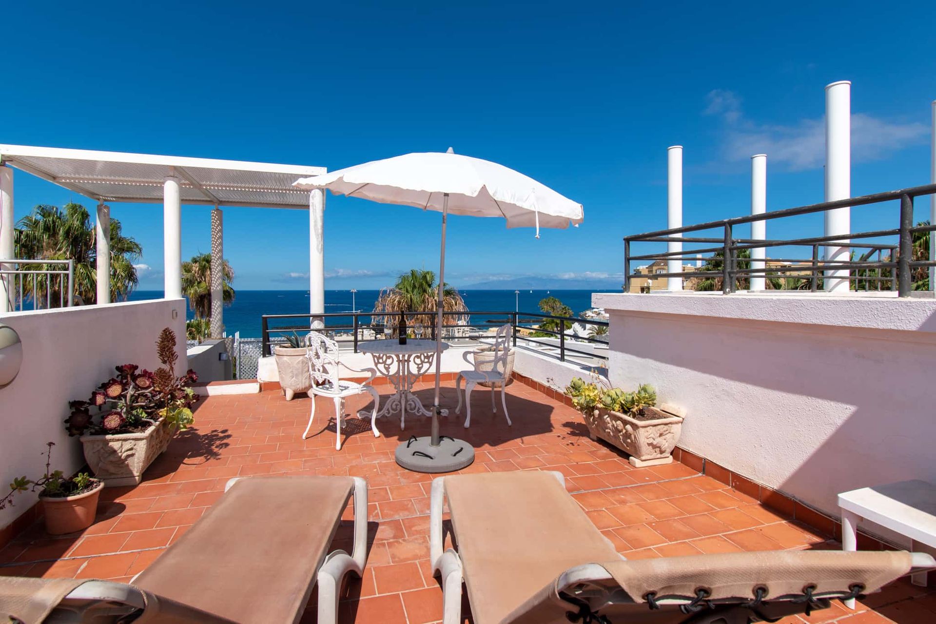 Roof terrace with sun loungers, patio table and chairs and sun umbrella with sea views, Los Olivos, Costa Adeje, Tenerife.
