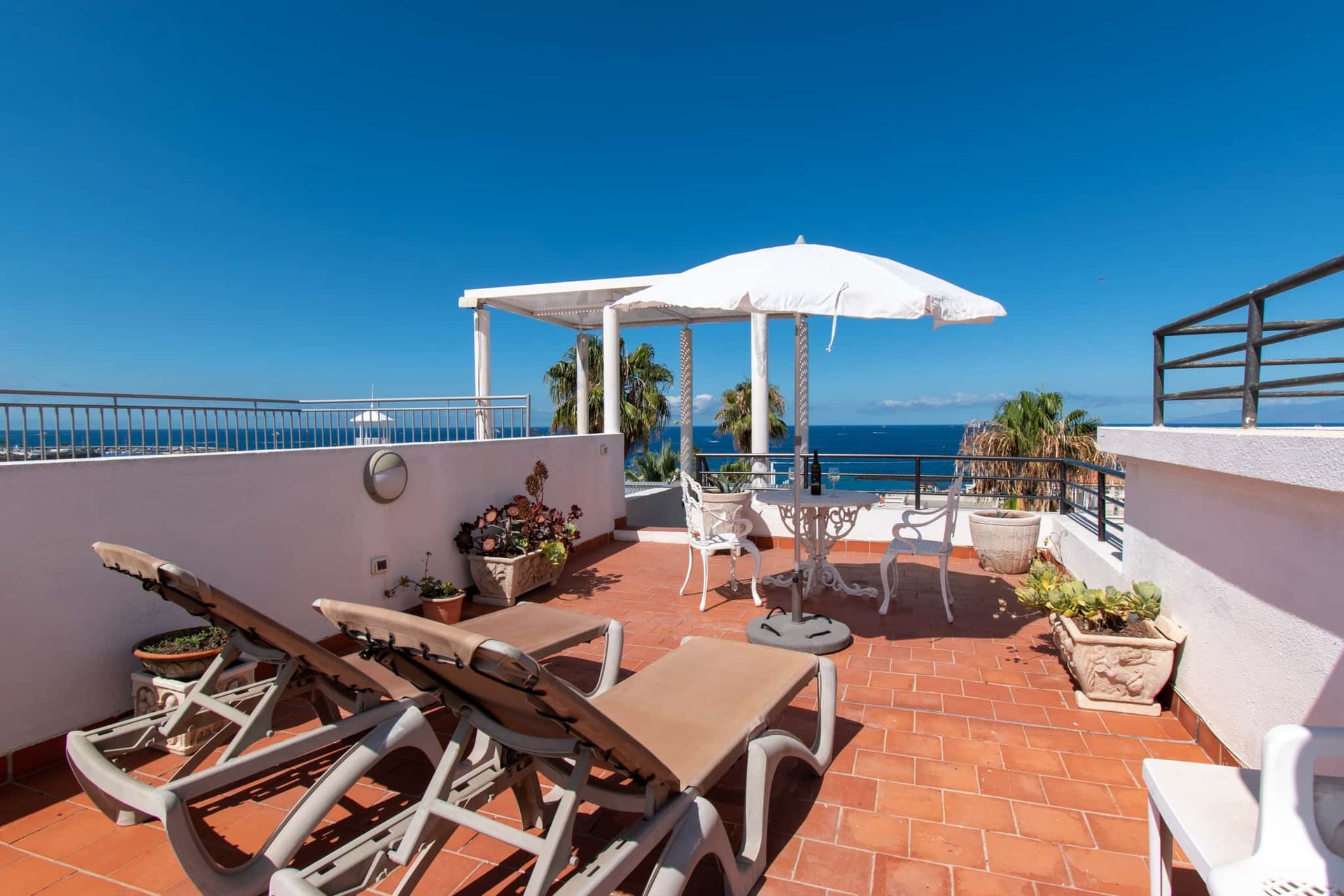 Roof terrace with sun loungers, patio table and chairs, sun umbrella and sea view, Los Olivos, Costa Adeje, Tenerife.