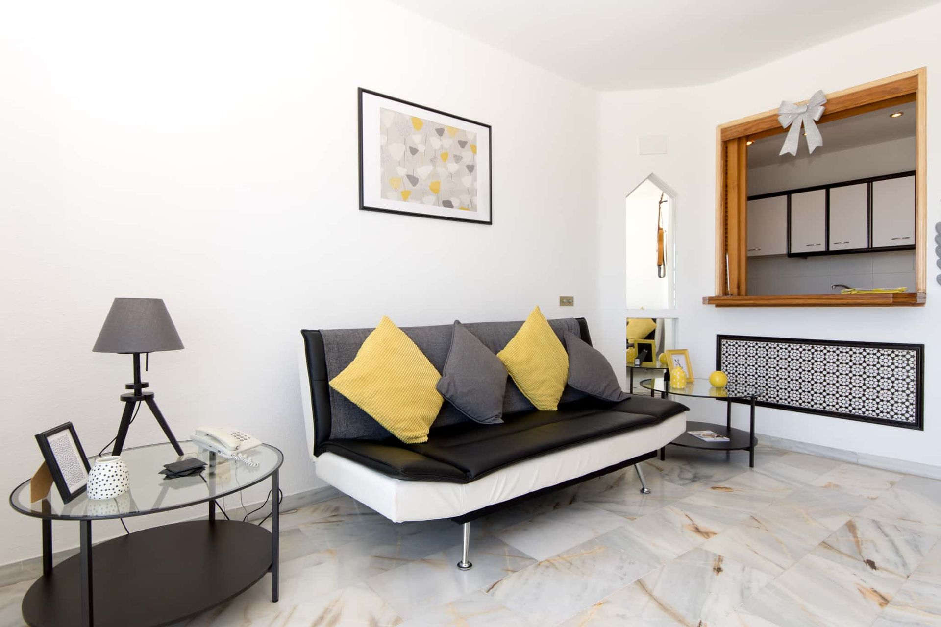 A living room with a black couch and yellow pillows