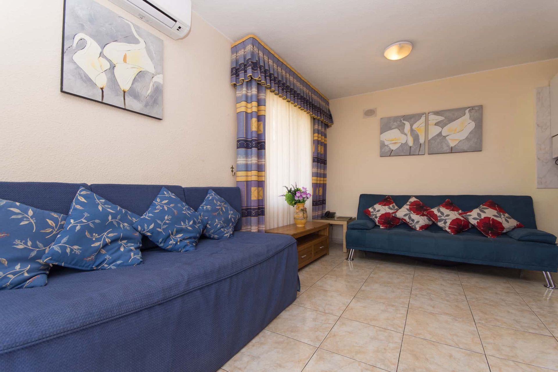 A living room with a black couch and yellow pillows