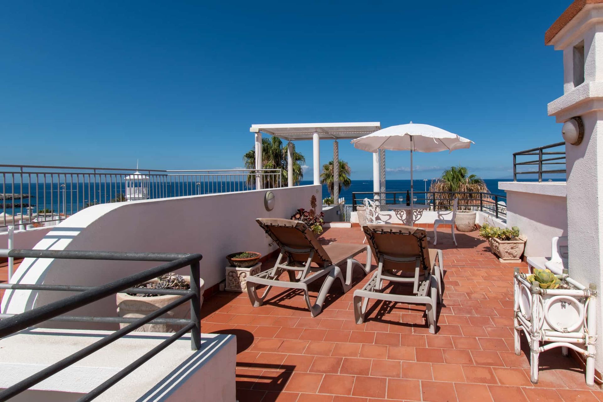 Roof terrace with sun loungers, patio table and chairs, sun umbrella and sea views, Los Olivos, Costa Adeje, Tenerife.