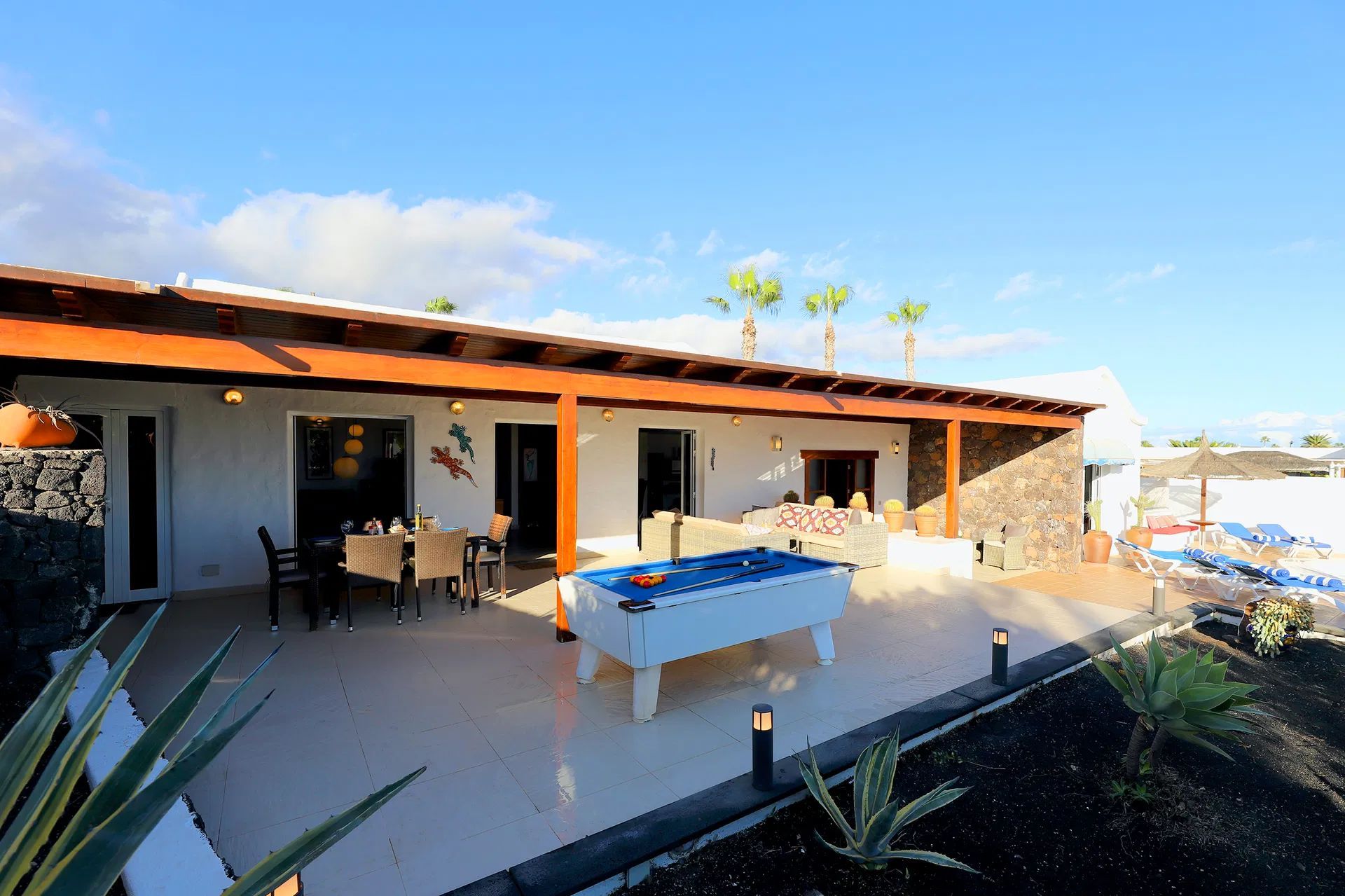 A patio of a white house with outdoor dining set under blue sky. Villa Salvo | Los Mojones | Puerto del Carmen | Lanzarote.