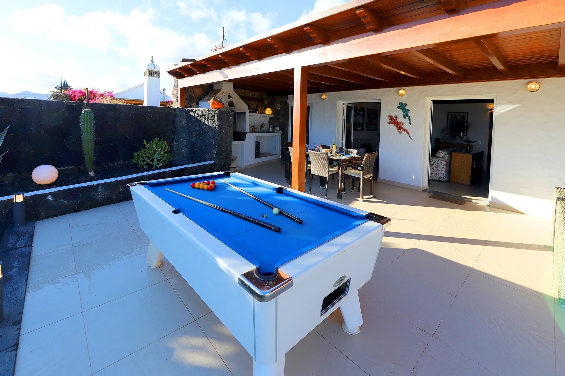 Pool table on an outdoor patio with a pergola, overlooking a sunny, white building. Villa Salvo | Los Mojones | Puerto del Carmen | Lanzarote.