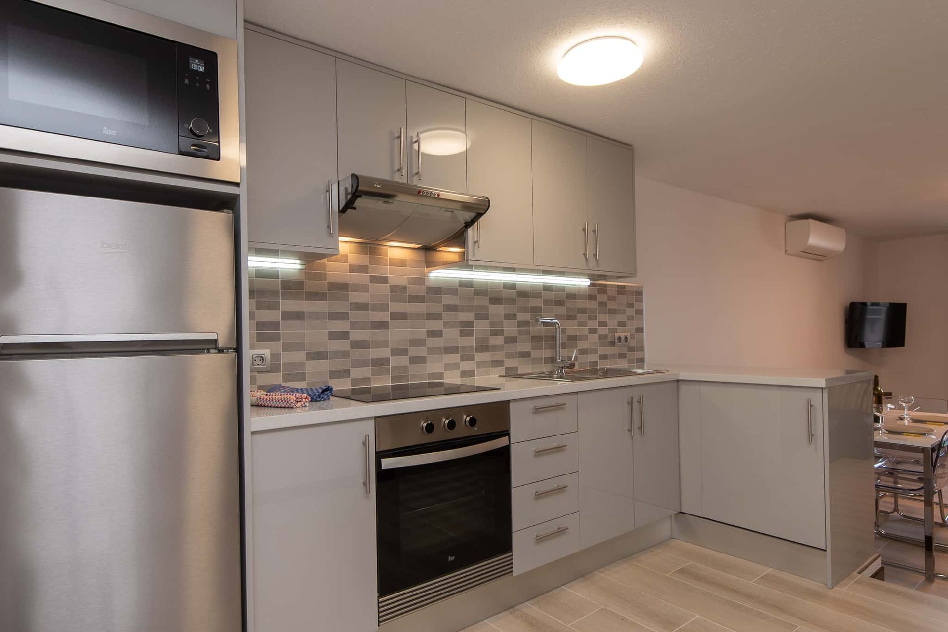 Kitchen with tall fridge freezer, microwave, oven, hob, extractor fan, sink, air conditioning at Parque Santiago II, Playa de las Americas, Tenerife