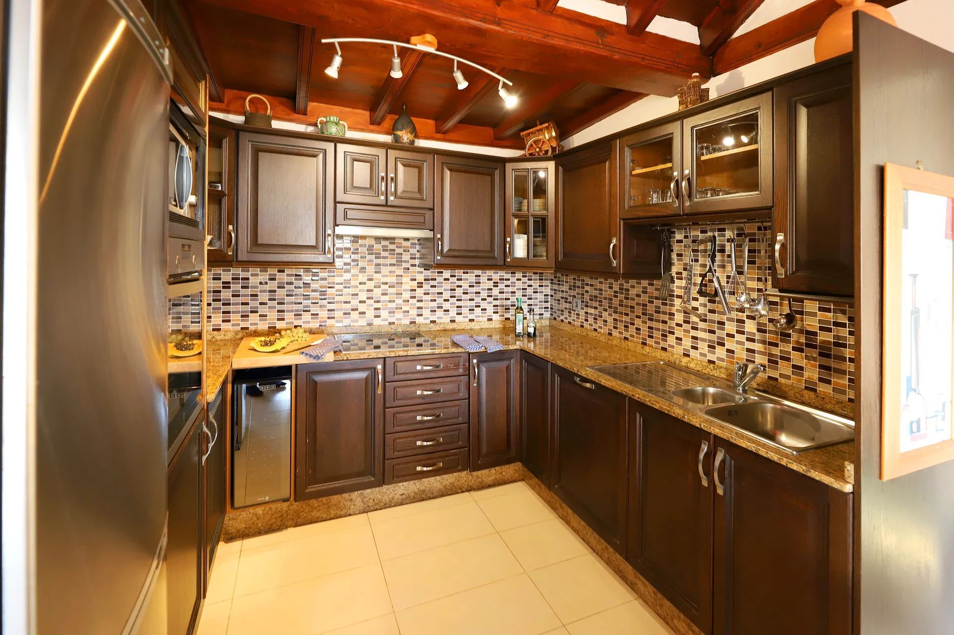 Dark wood kitchen with tile backsplash, granite countertops, and stainless steel appliances. Villa Salvo | Los Mojones | Puerto del Carmen | Lanzarote.