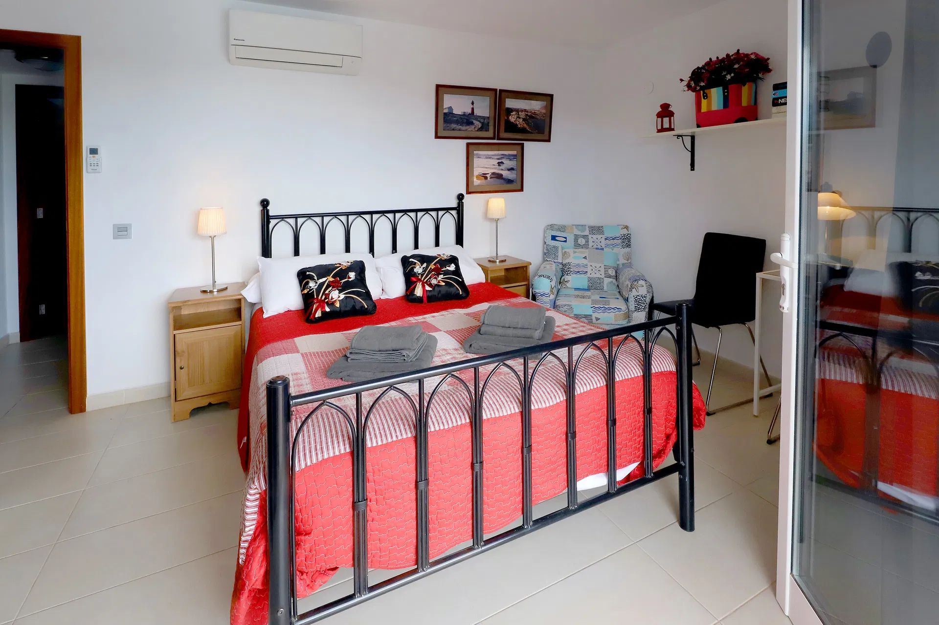 Bedroom with black metal bed, red bedding, nightstands, and artwork. Villa Salvo | Los Mojones | Puerto del Carmen | Lanzarote.