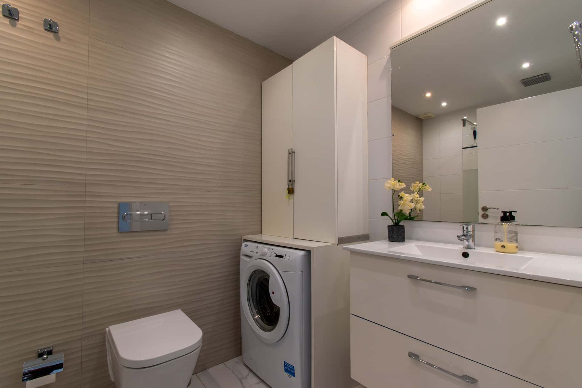 Bathroom with wash hand basin with mirror above, WC, washing machine, Club Atlantis, Costa Adeje, Tenerife.