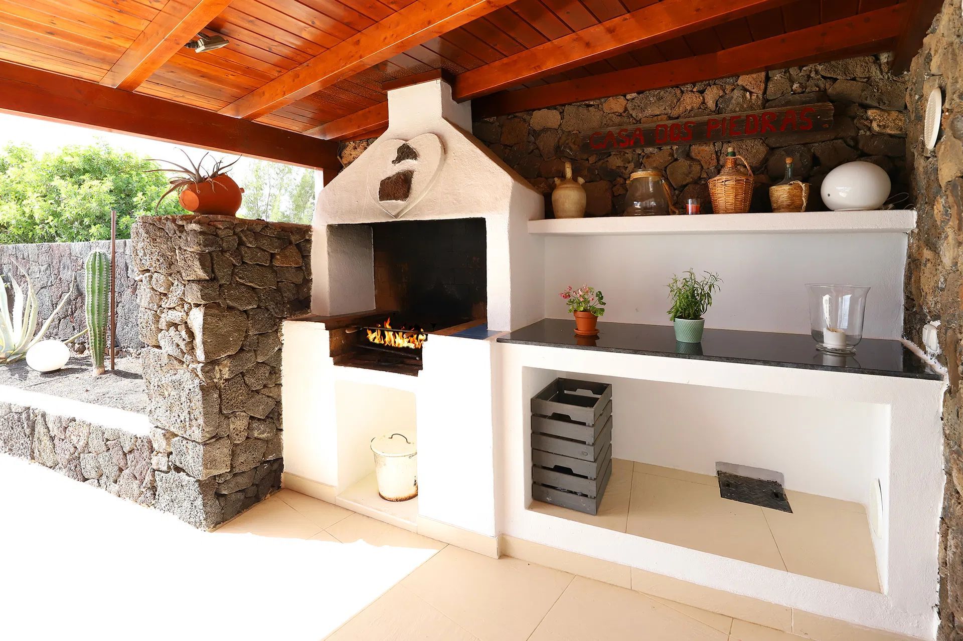 Outdoor barbecue with stone walls, wooden ceiling, and built-in counter. Villa Salvo | Los Mojones | Puerto del Carmen | Lanzarote.