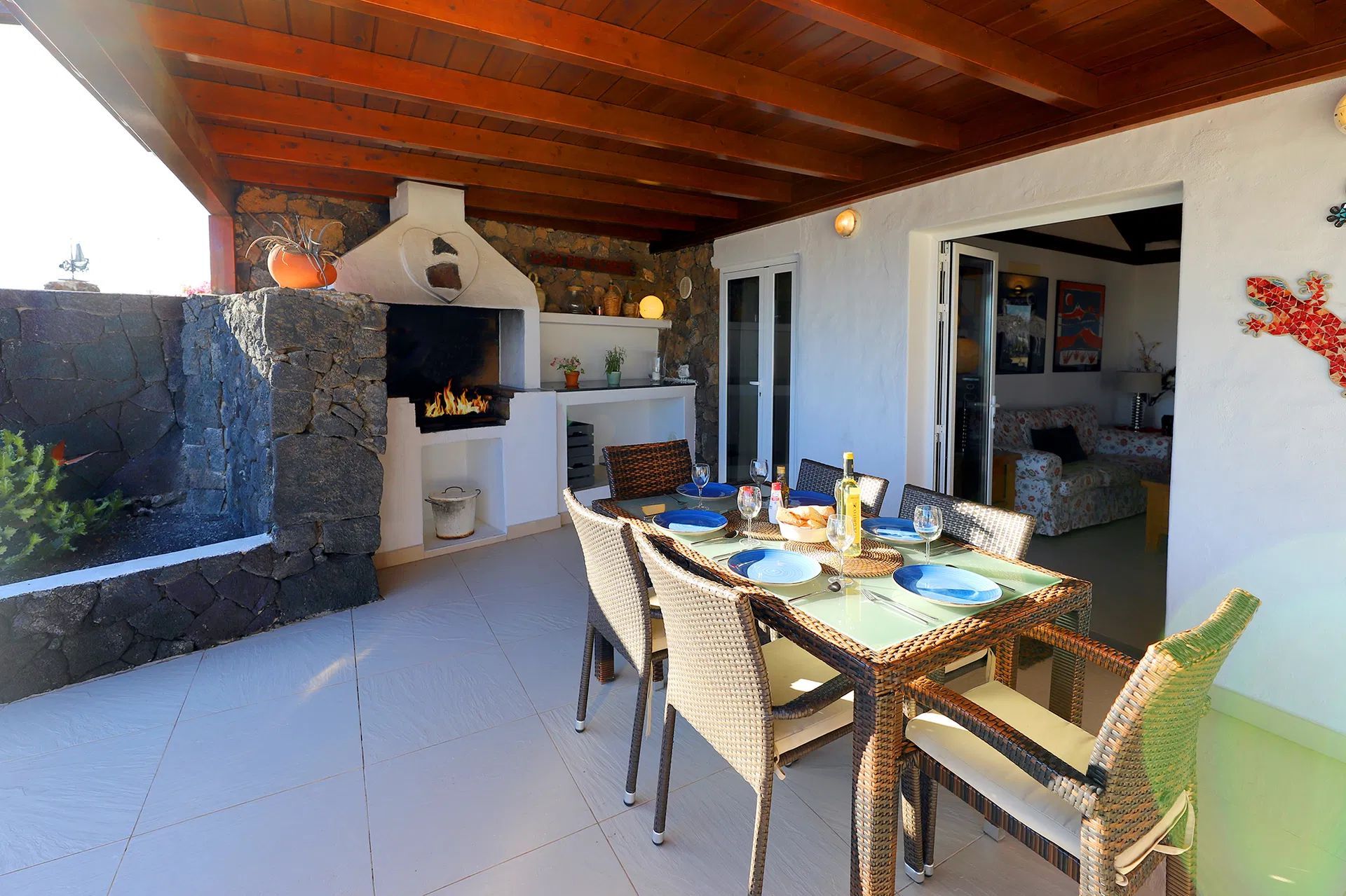 Outdoor patio with dining table set for a meal near a grill and a white house in daylight. Villa Salvo | Los Mojones | Puerto del Carmen | Lanzarote.