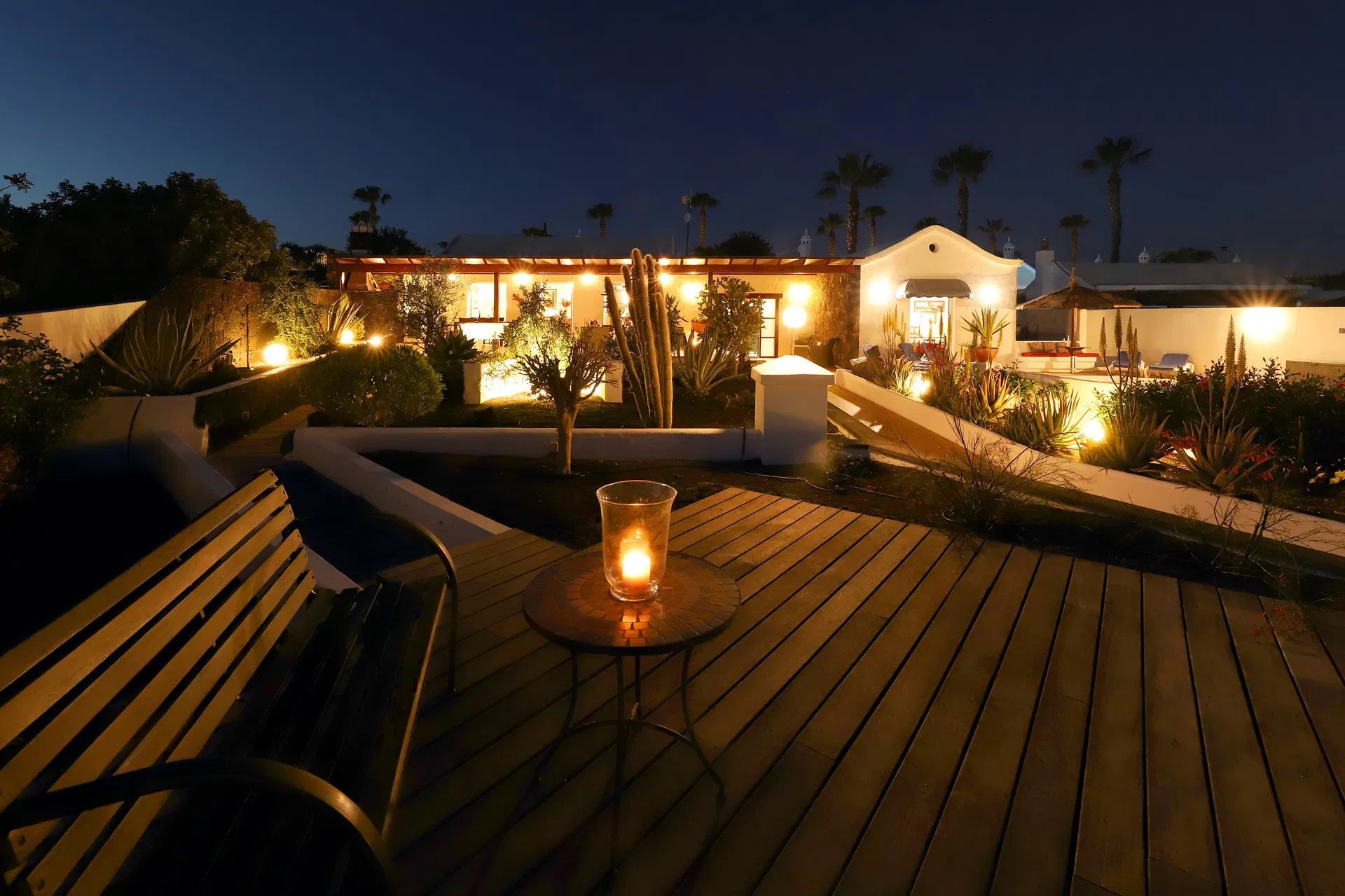 Night time patio with lit candles and house in the background, warm lights against dark sky. Villa Salvo | Los Mojones | Puerto del Carmen | Lanzarote.