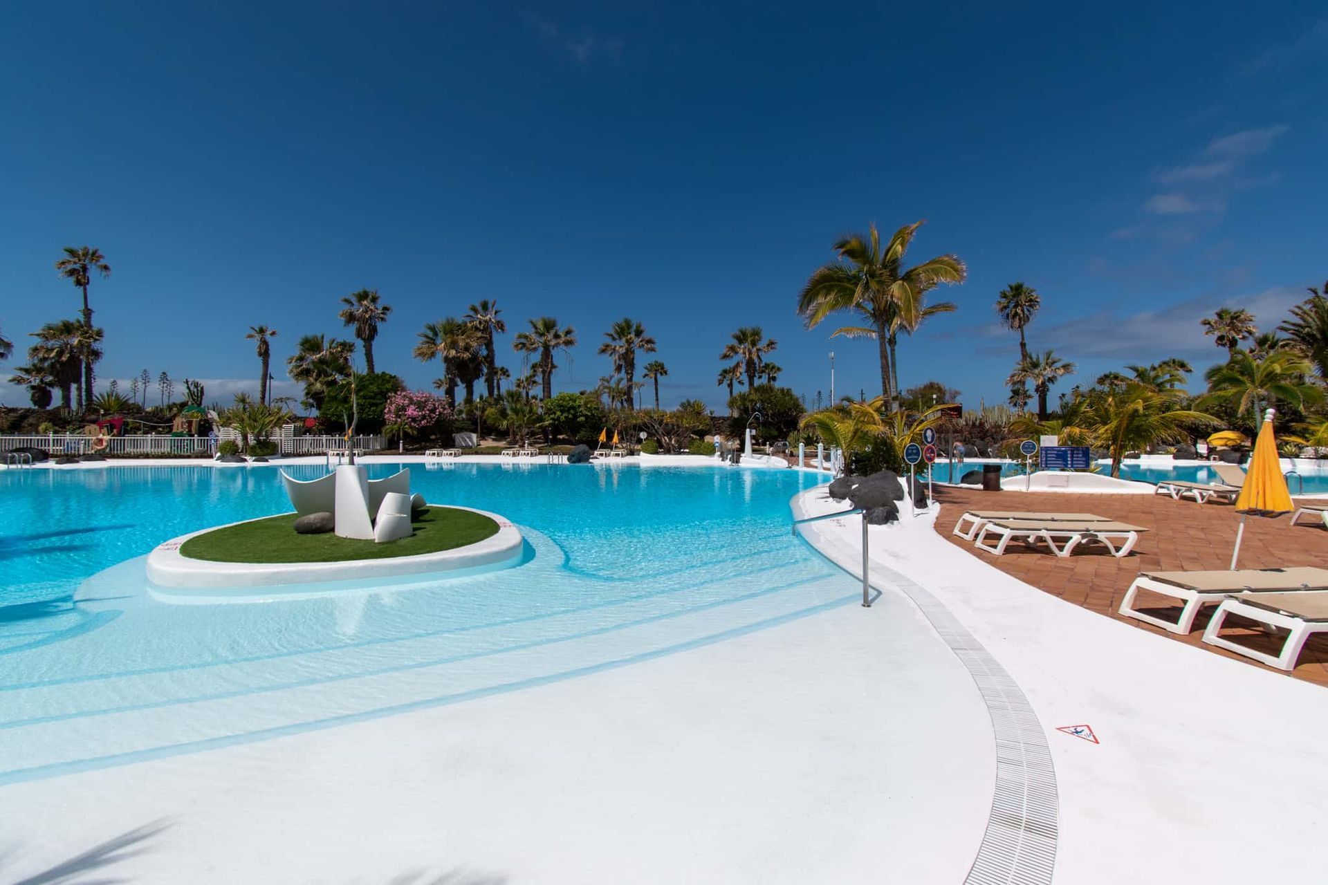 Pool on Parque Santiago IV surrounded by sun loungers and sun parasols.