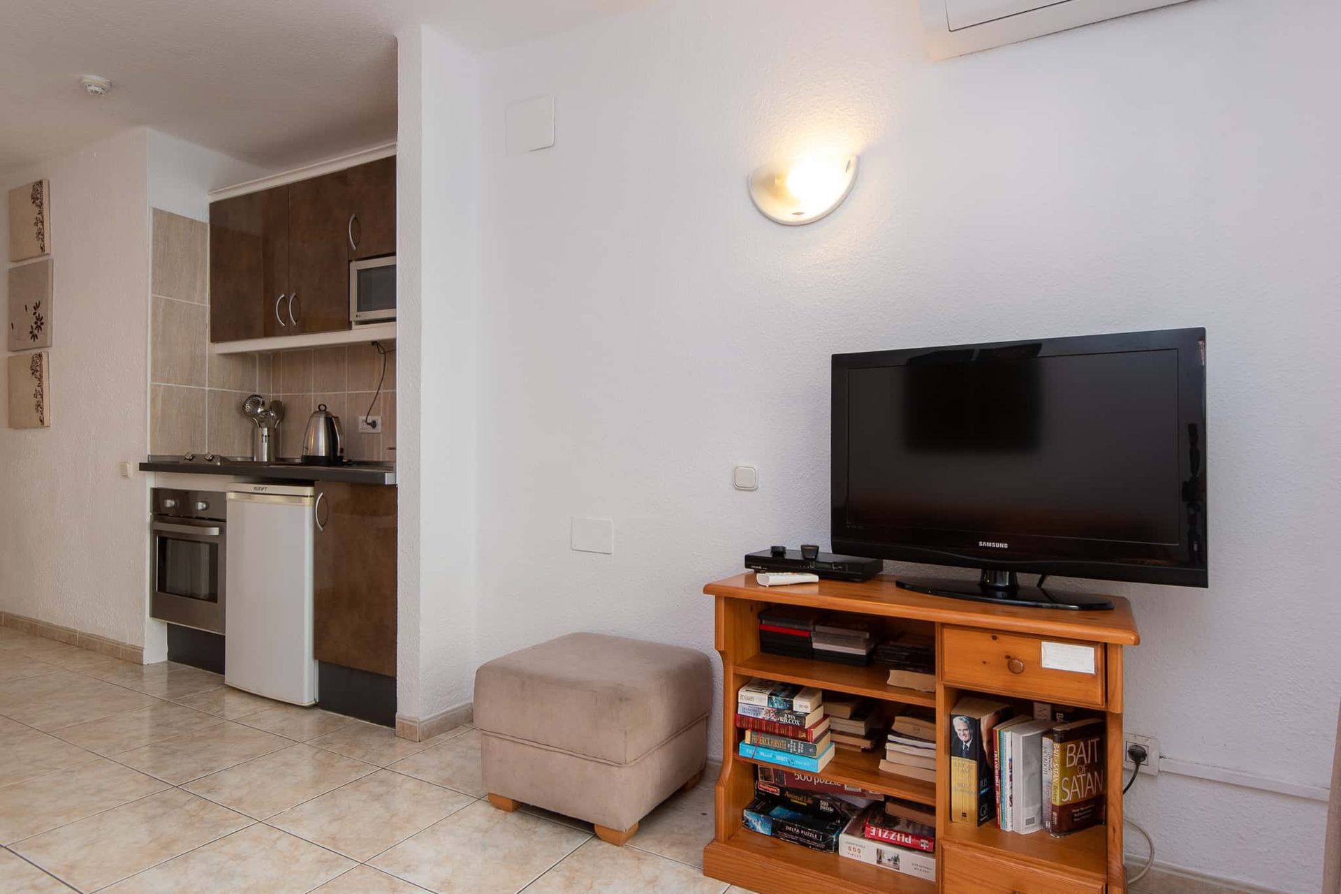 A living room with a couch , television and a guitar hanging on the wall.