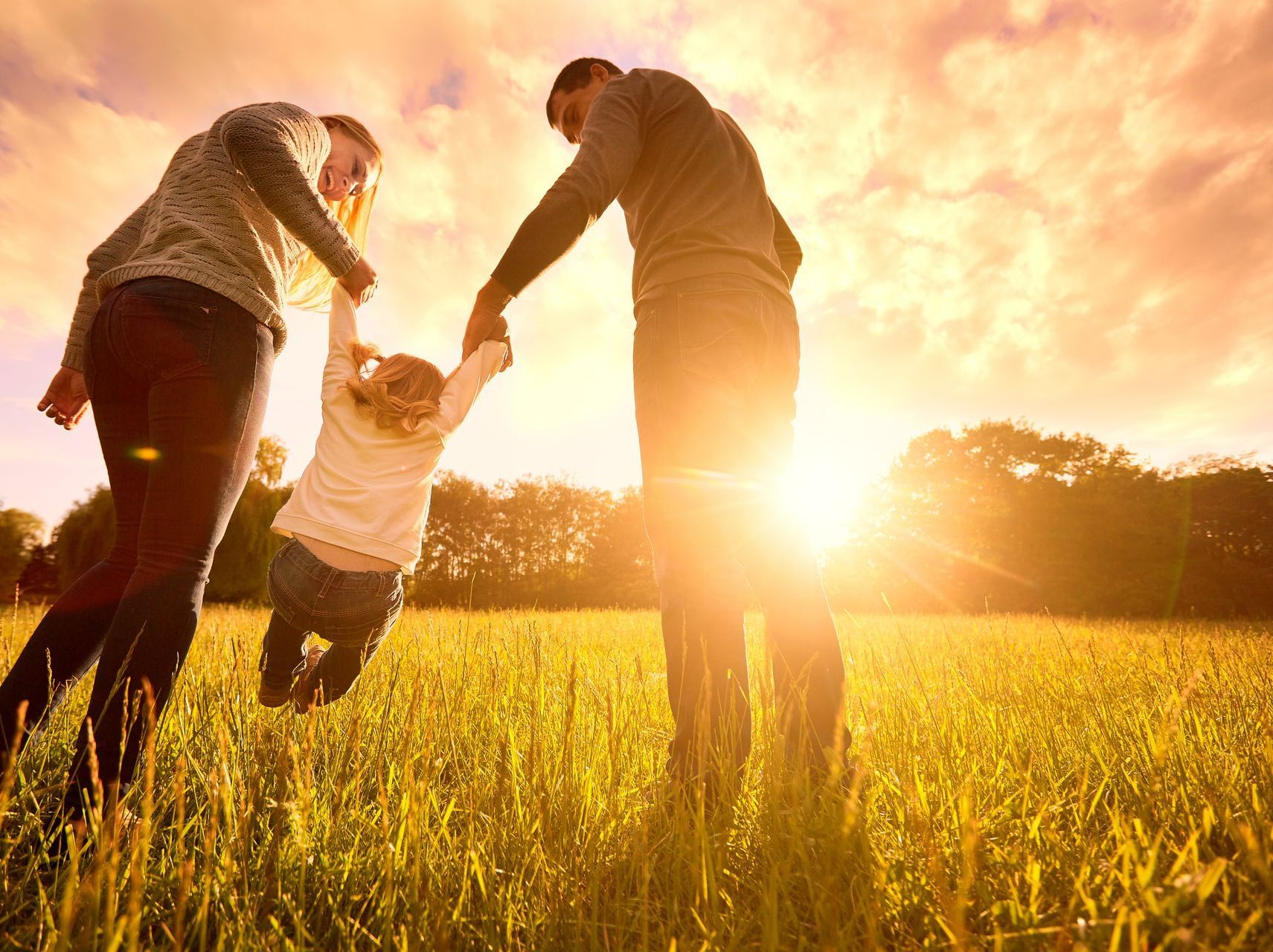 Deux parents joue avec leur fille dans un champs