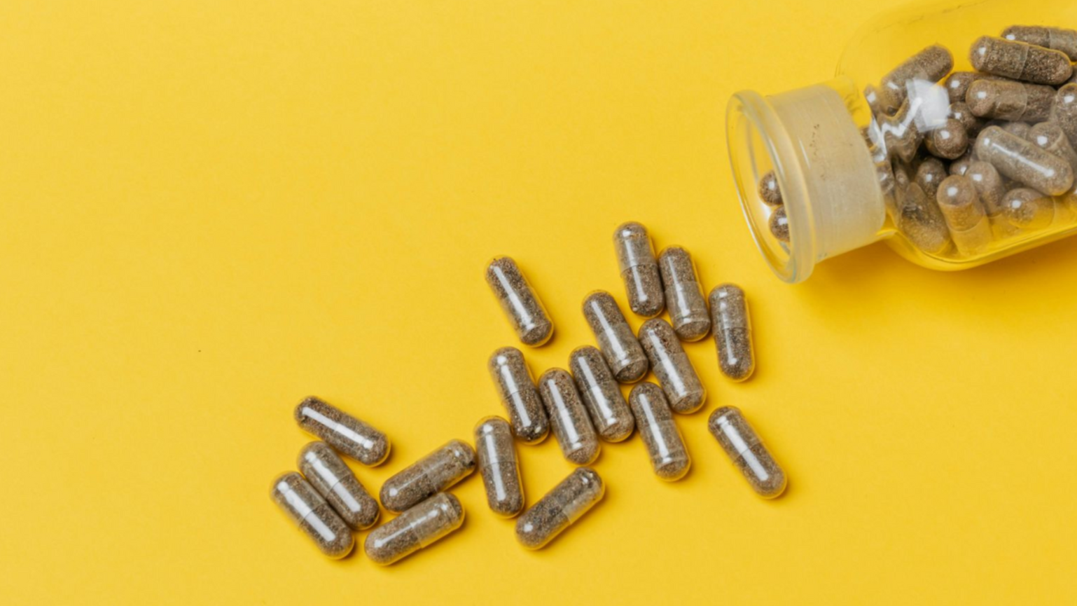 Natürliche Kapseln auf einem Holztablett mit grünen Blättern im Hintergrund – Private Label Nahrungsergänzungsmittel mit pflanzlichen Inhaltsstoffen.