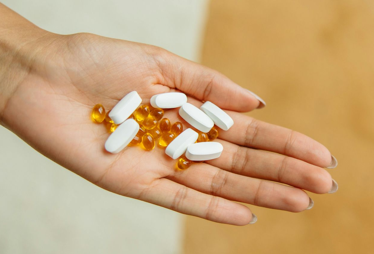 Eine Person hält eine Handvoll Kapseln, die aus einem braunen Glasbehälter geschüttet werden – hochwertige Private Label Nahrungsergänzungsmittel in Kapselform.