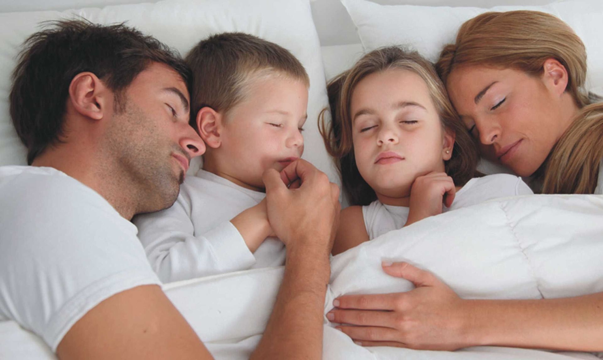 Una familia está durmiendo junta en una cama.