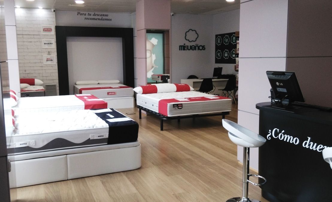 Una tienda llena de colchones y un monitor de computadora.