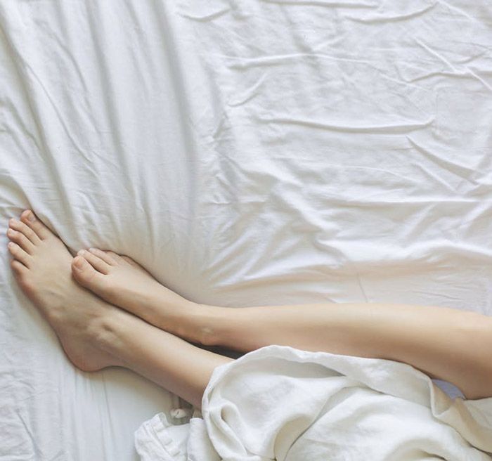 Una persona acostada en una cama con las piernas cruzadas