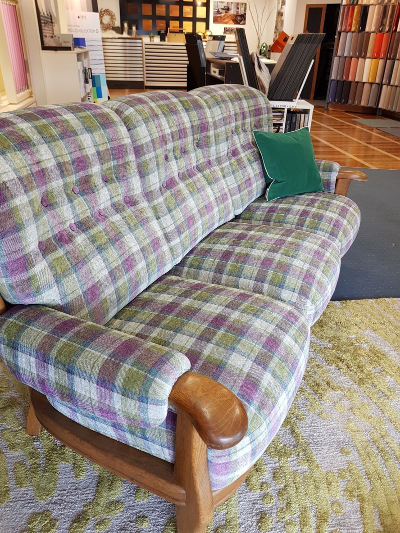 Ein Sofa mit kariertem Kissen steht auf einem Teppich in einem Wohnzimmer