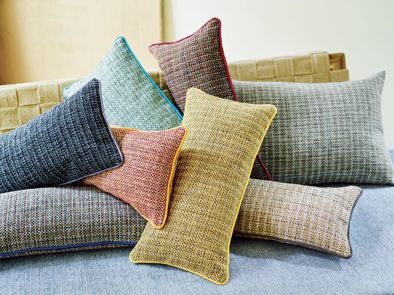 Auf einem Sofa sind mehrere bunte Kissen übereinander gestapelt