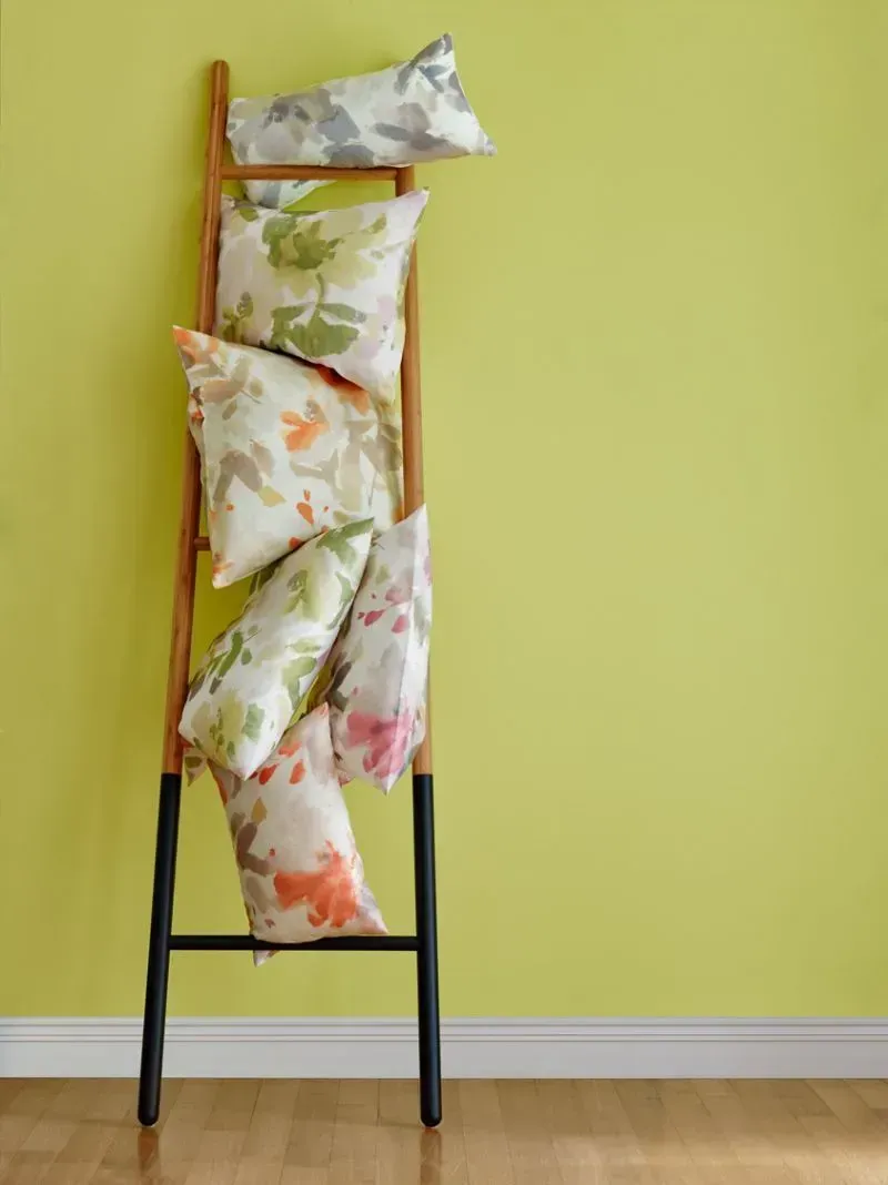 Eine Leiter voller bunter Kissen vor einer gelben Wand