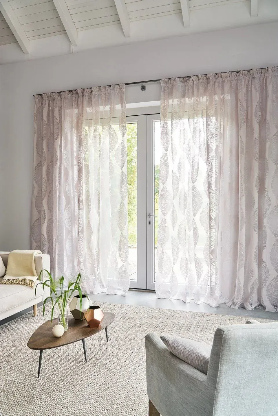 Ein Wohnzimmer mit Couch, Sessel, Couchtisch und Vorhängen