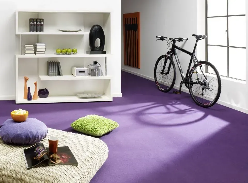 Ein Wohnzimmer mit lila Teppich und einem Fahrrad auf dem Boden