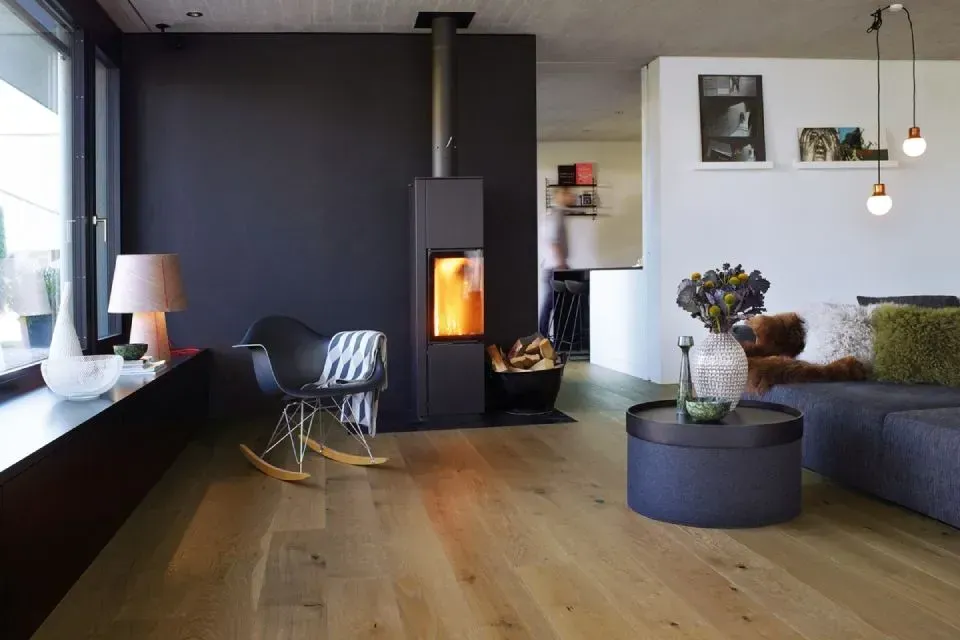 Ein Wohnzimmer mit Schaukelstuhl, Couch, Tisch und Kamin