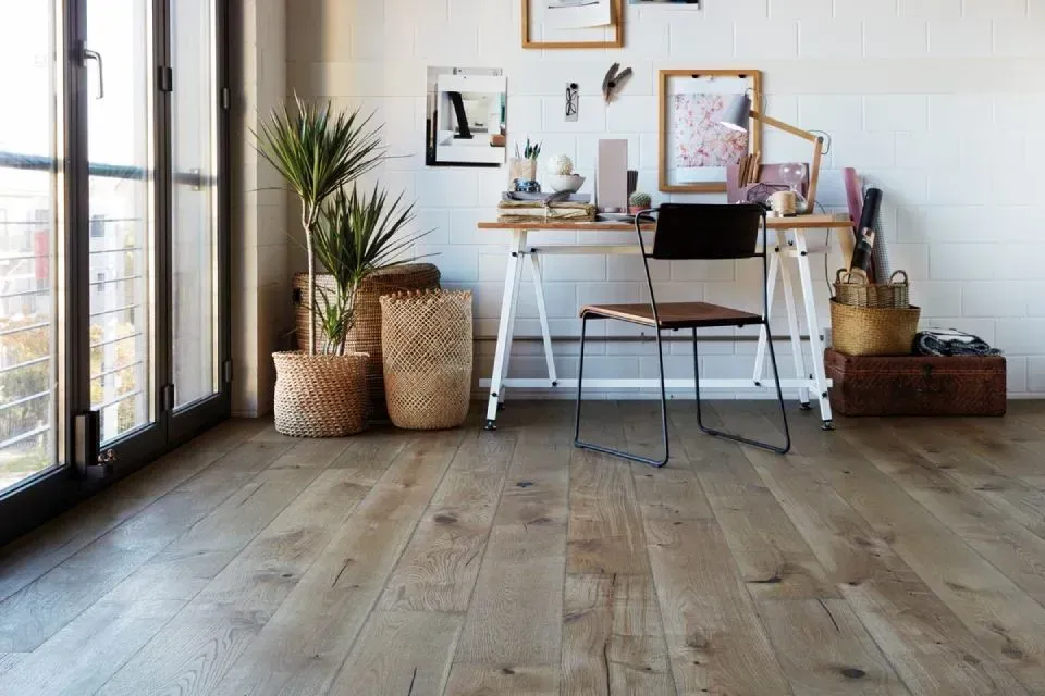 Ein Holzboden in einem Zimmer mit einem Schreibtisch und einem Stuhl