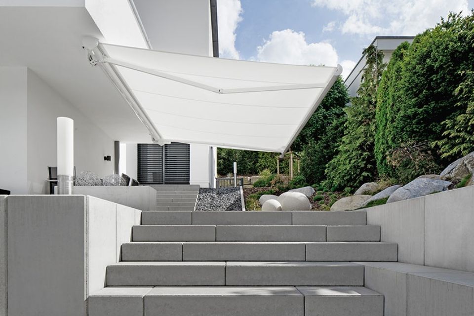 Über einer Treppe, die zu einem Haus hinaufführt, hängt eine weiße Markise