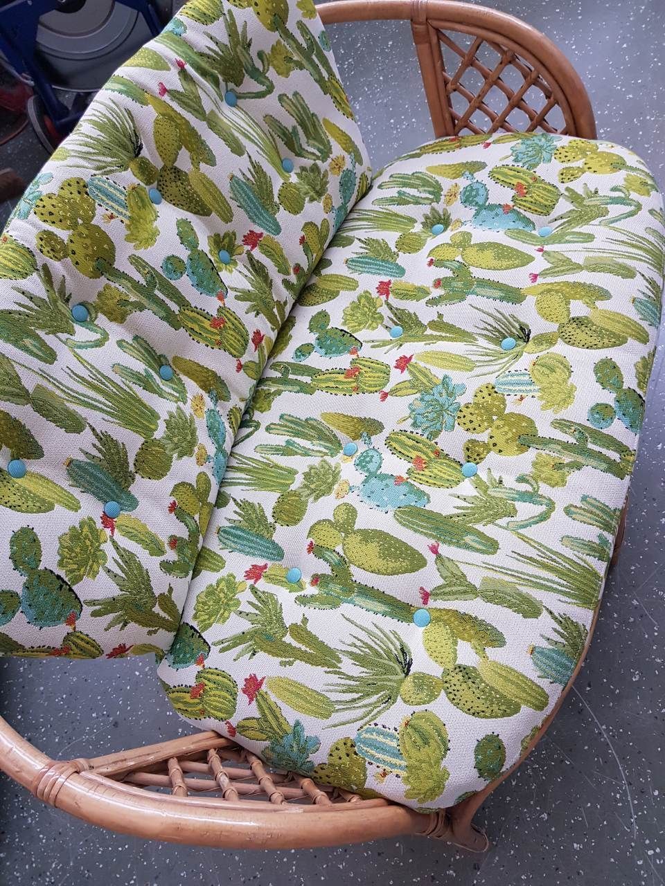 Ein Korbsofa mit einem Kissen mit Kaktusmuster