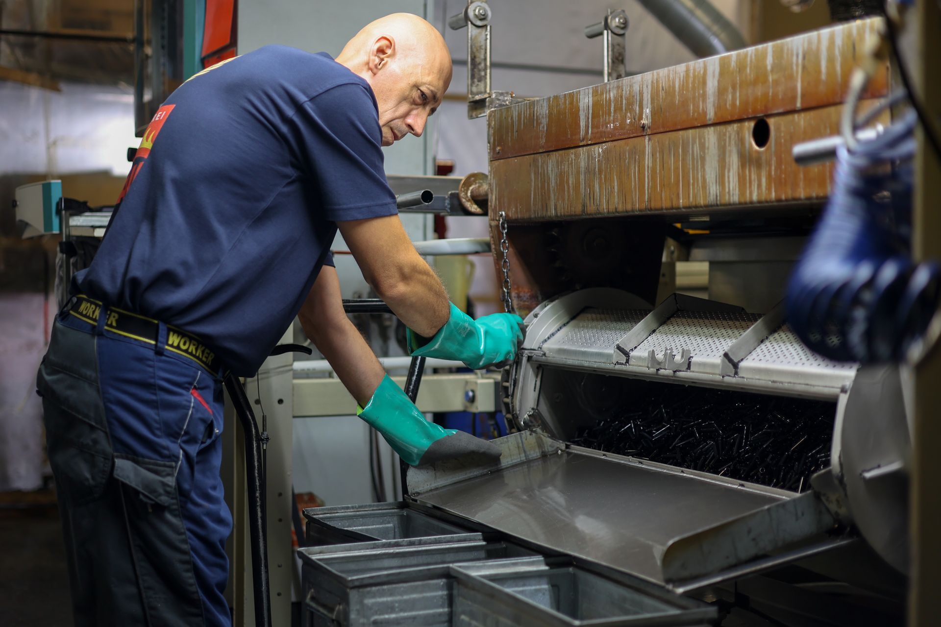 Ein Mann mit Handschuhen arbeitet an einer Maschine in einer Fabrik.