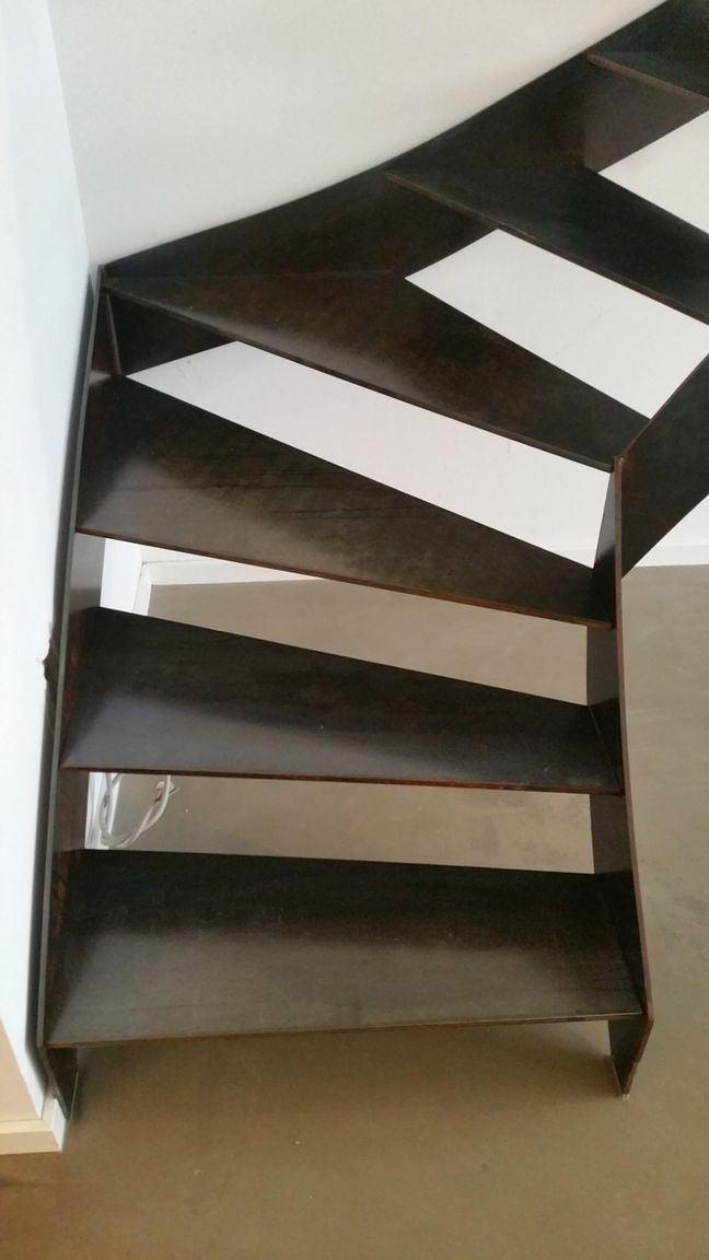 Dunkelbraune Wendeltreppe mit offenen Setzstufen in einer weiß getünchten Ecke