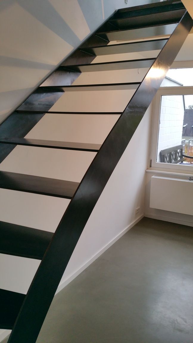 Moderne Treppe mit schwarzem Metallrahmen und weißen Stufen in einem hellen Interieur