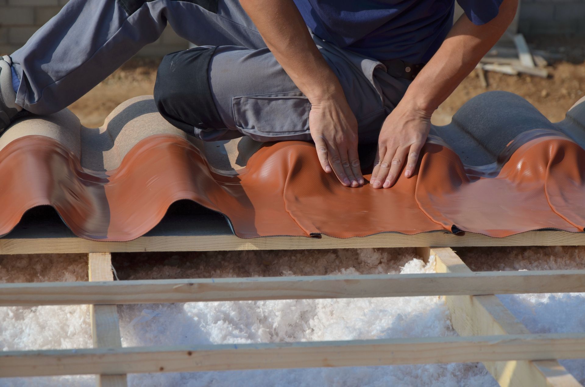 Personne posant des tuiles sur un toit.