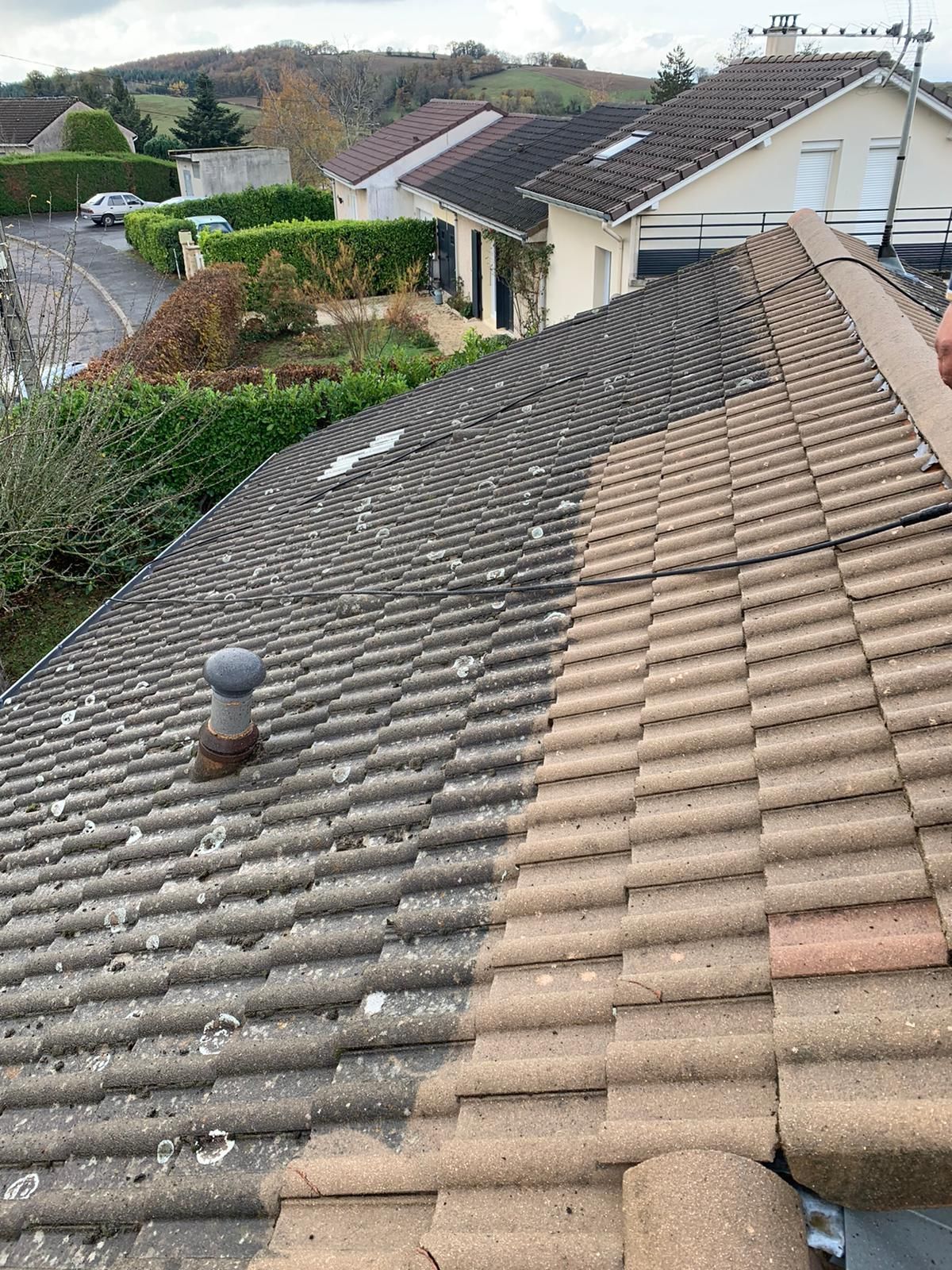 Nettoyage d'un toit ; moitié grisâtre couvert de mousse..