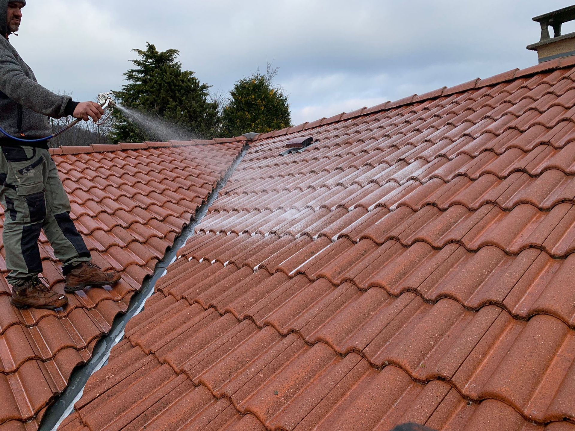 Couvreur appliquant un produit sur la toiture.