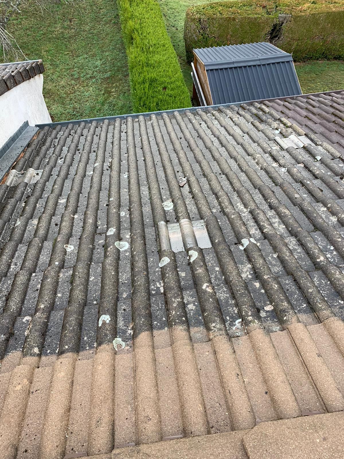 Vue aérienne d'un toit de tuiles délavé par les intempéries, recouvert de mousse et d'algues.