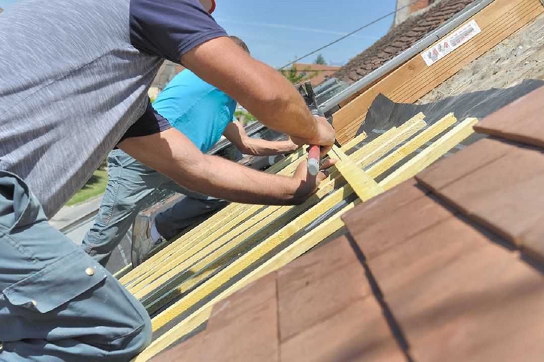 Deux personnes posent des tuiles par une journée ensoleillée.