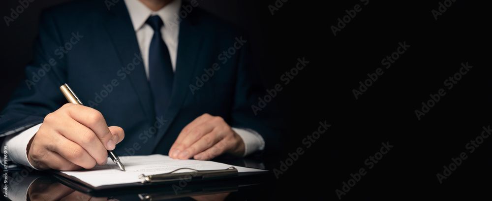 Mann unterschreibt ein Dokument. MMA Anwaltsbüro