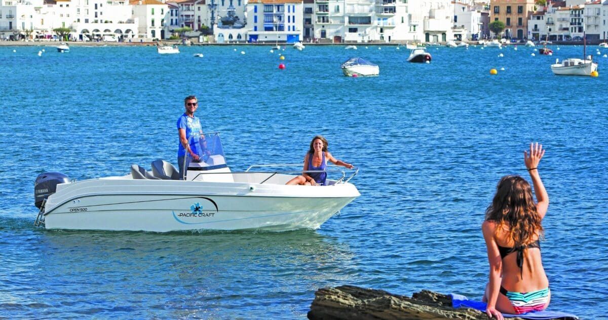 Una mujer en bikini está sentada en una roca al lado de un barco en el agua.