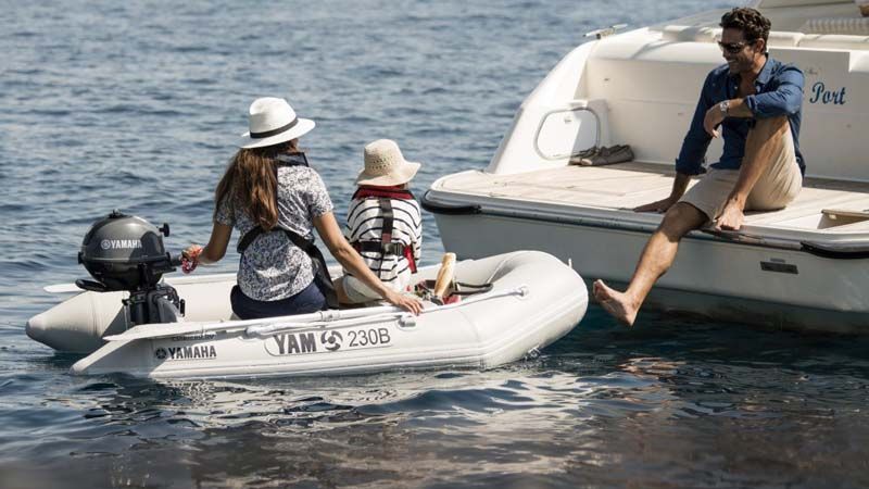 Un hombre está sentado en la parte trasera de un bote con dos personas en un bote pequeño.