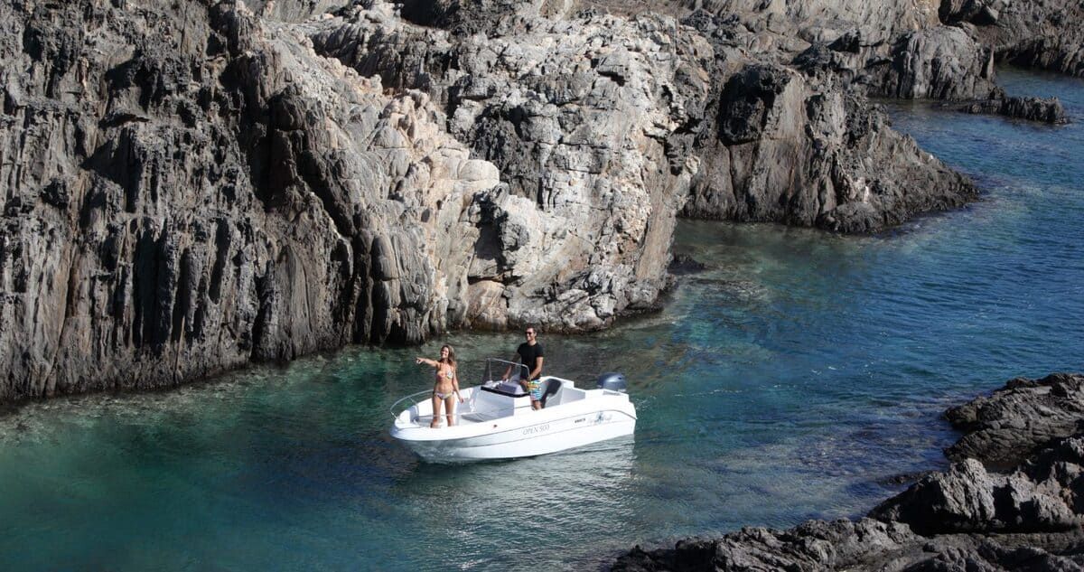 Un barco flota sobre un cuerpo de agua al lado de una costa rocosa.