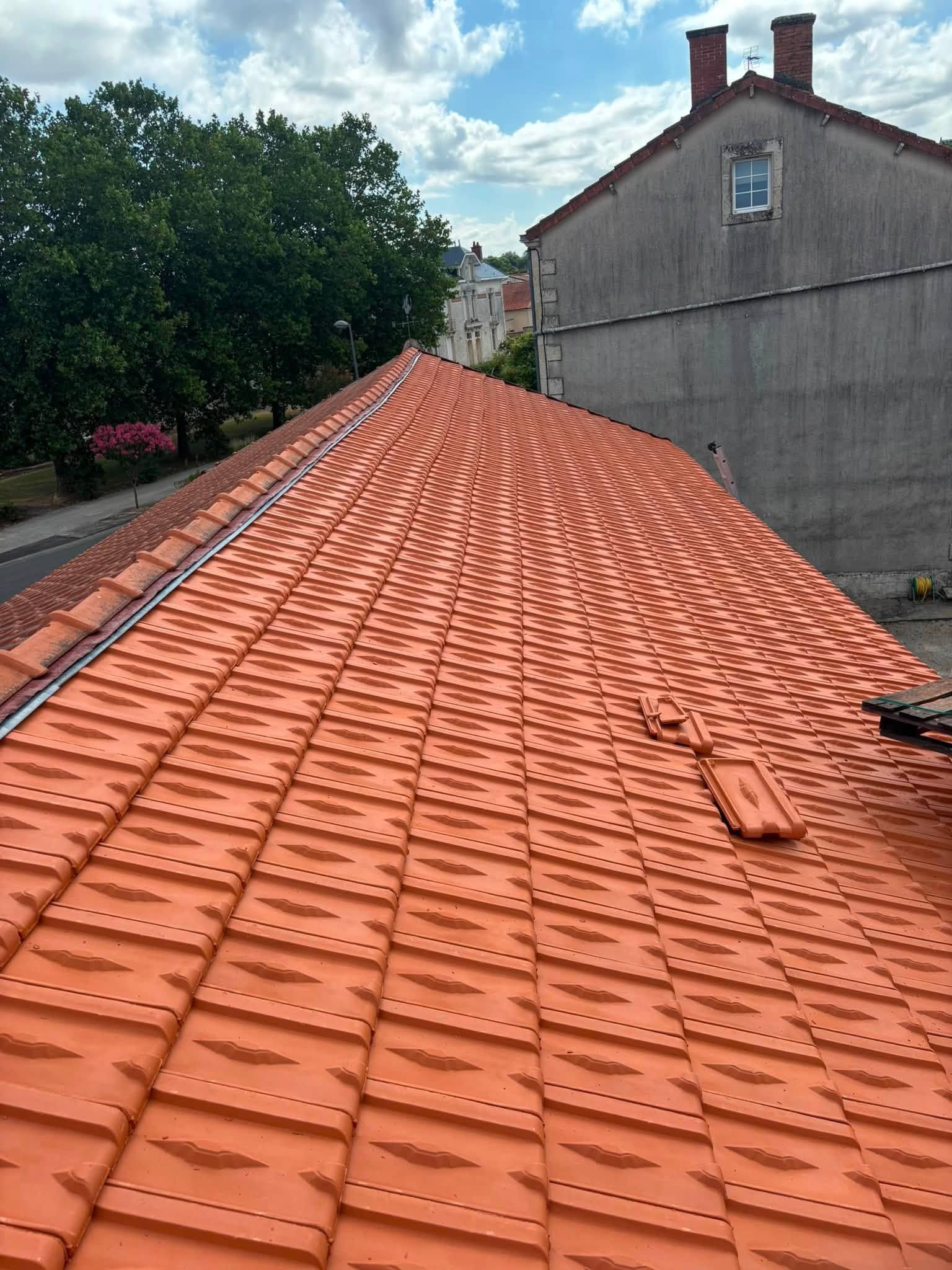 Toit de tuiles rouges avec échelle sur fond de ciel bleu, vu d'en bas