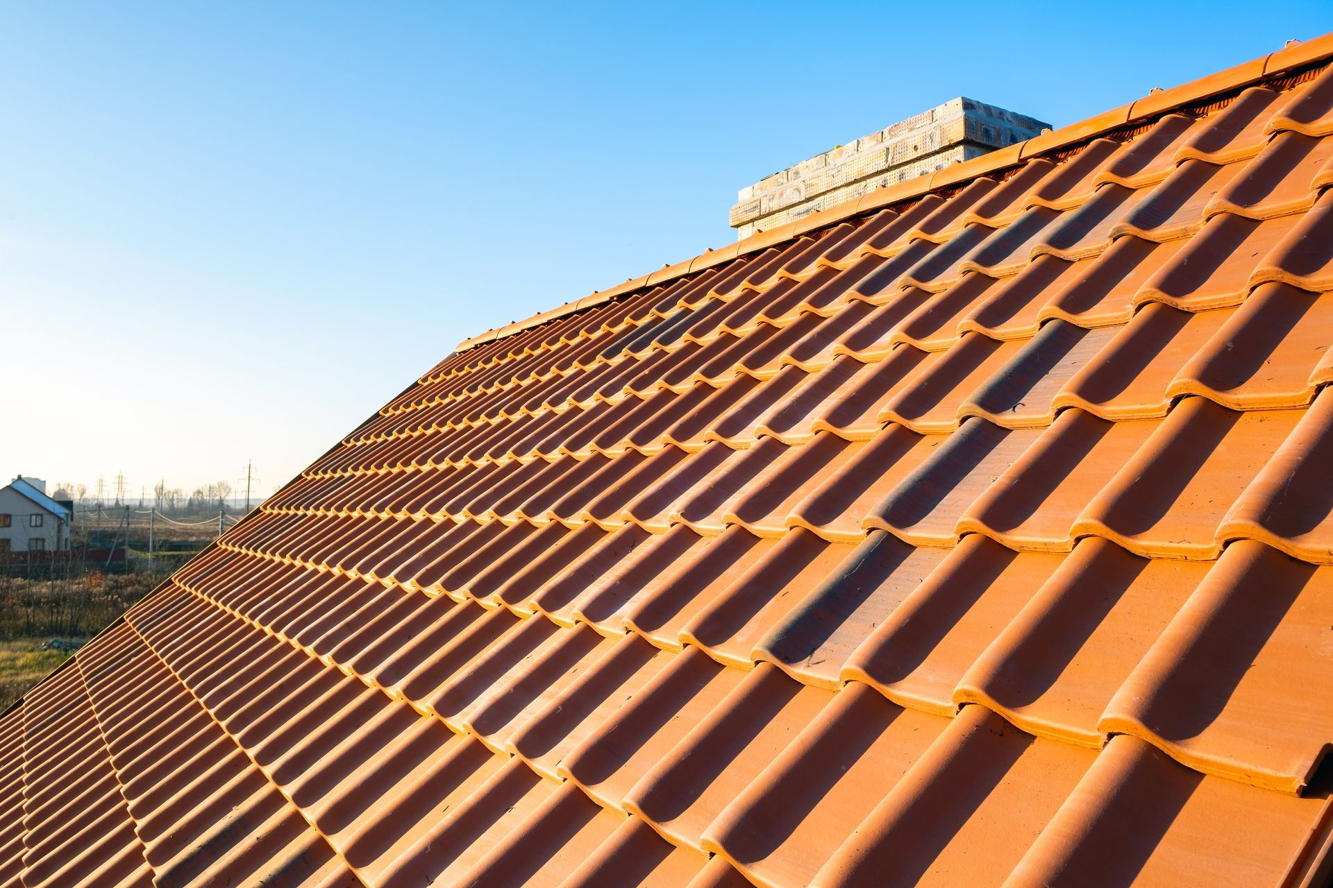 Tuiles de terre cuite rouge sur un toit en pente sous un ciel bleu clair