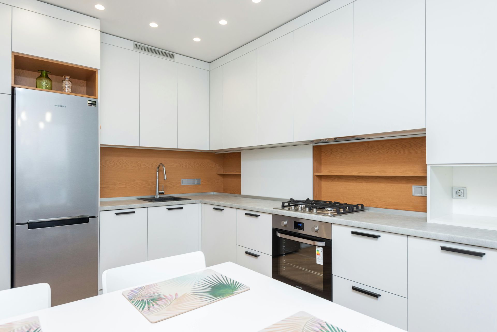 Una cocina con gabinetes blancos y electrodomésticos de acero inoxidable.