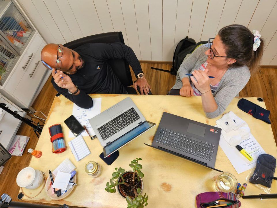 Ein Mann und eine Frau sitzen mit Laptops an einem Tisch.